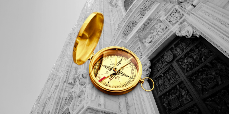 A golden compass in front of a temple.